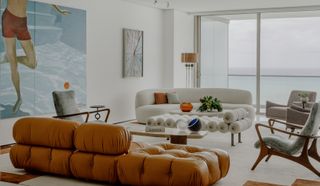 A living room with a white sofa, and a leather sofa in tan color