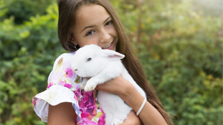 Brunette girl holding a white rabbit on International Rabbit Day