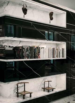 A black and white marble five shelf display featuring Saint Laurent Rive Droite books in the middle.