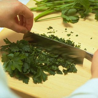 chef cutting coriander with kitchen knife