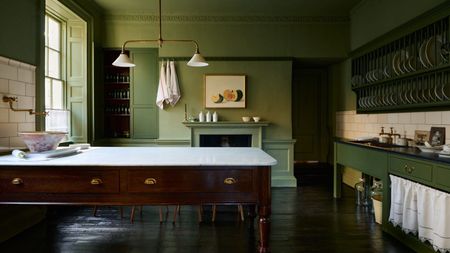 Green deVOL Heirloom kitchen featuring a freestanding Dairy Table with a marble worktop, open plate rack storage, painted cabinetry, dark wood flooring and period architectural details.