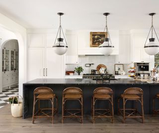 kitchen with black island and white cabinets with chandeliers above