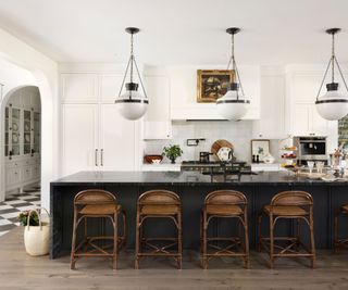 Kitchen with black island and white cabinets with chandelier above