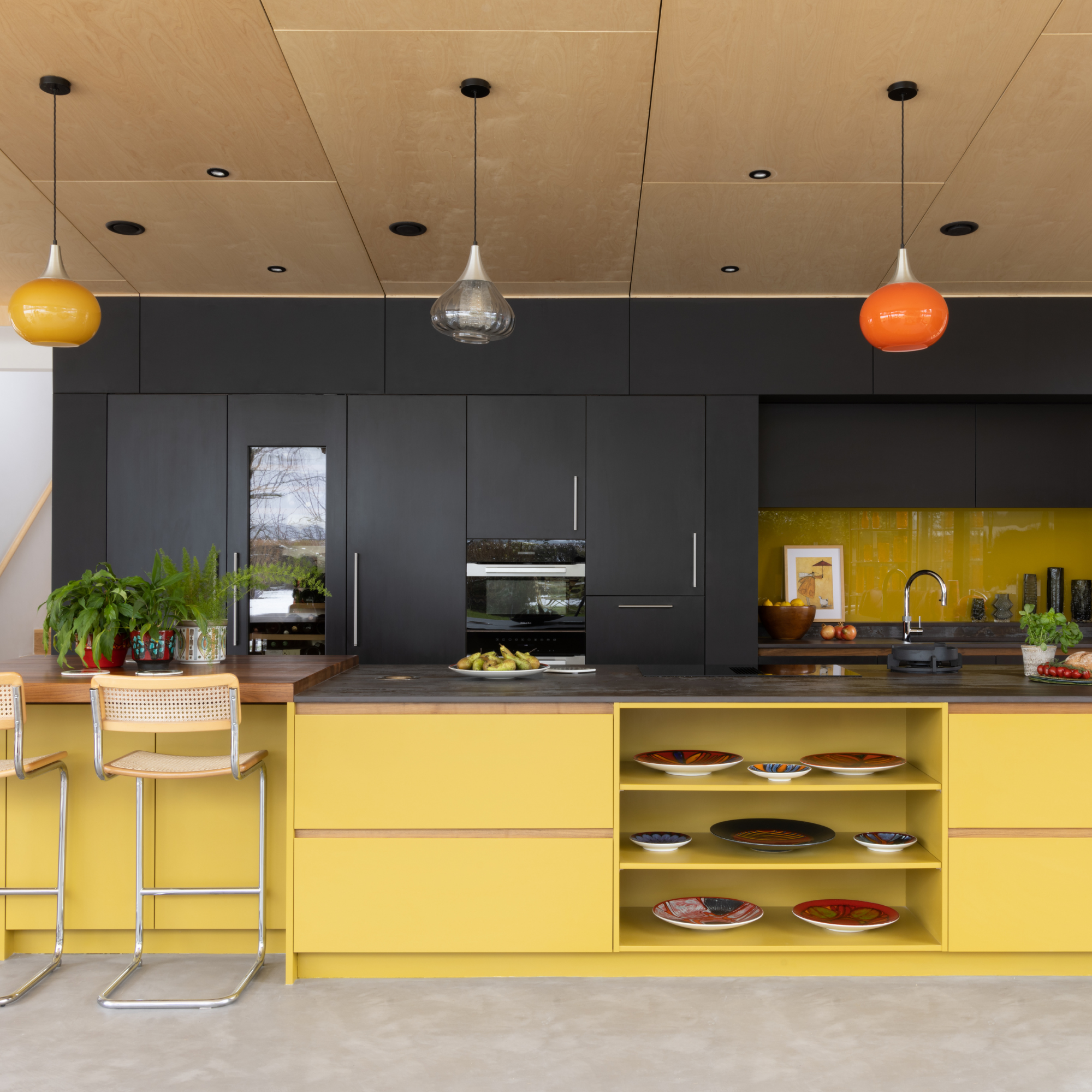 a yellow and black mid century kitchen with large glass pendants hanging from ceiling