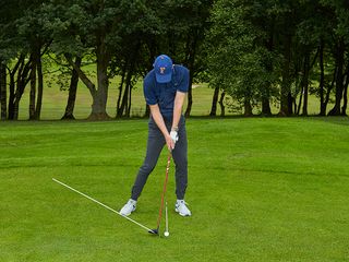 Ged Walters demonstrating the correct angle of attack for a fairway wood strike, using alignment sticks