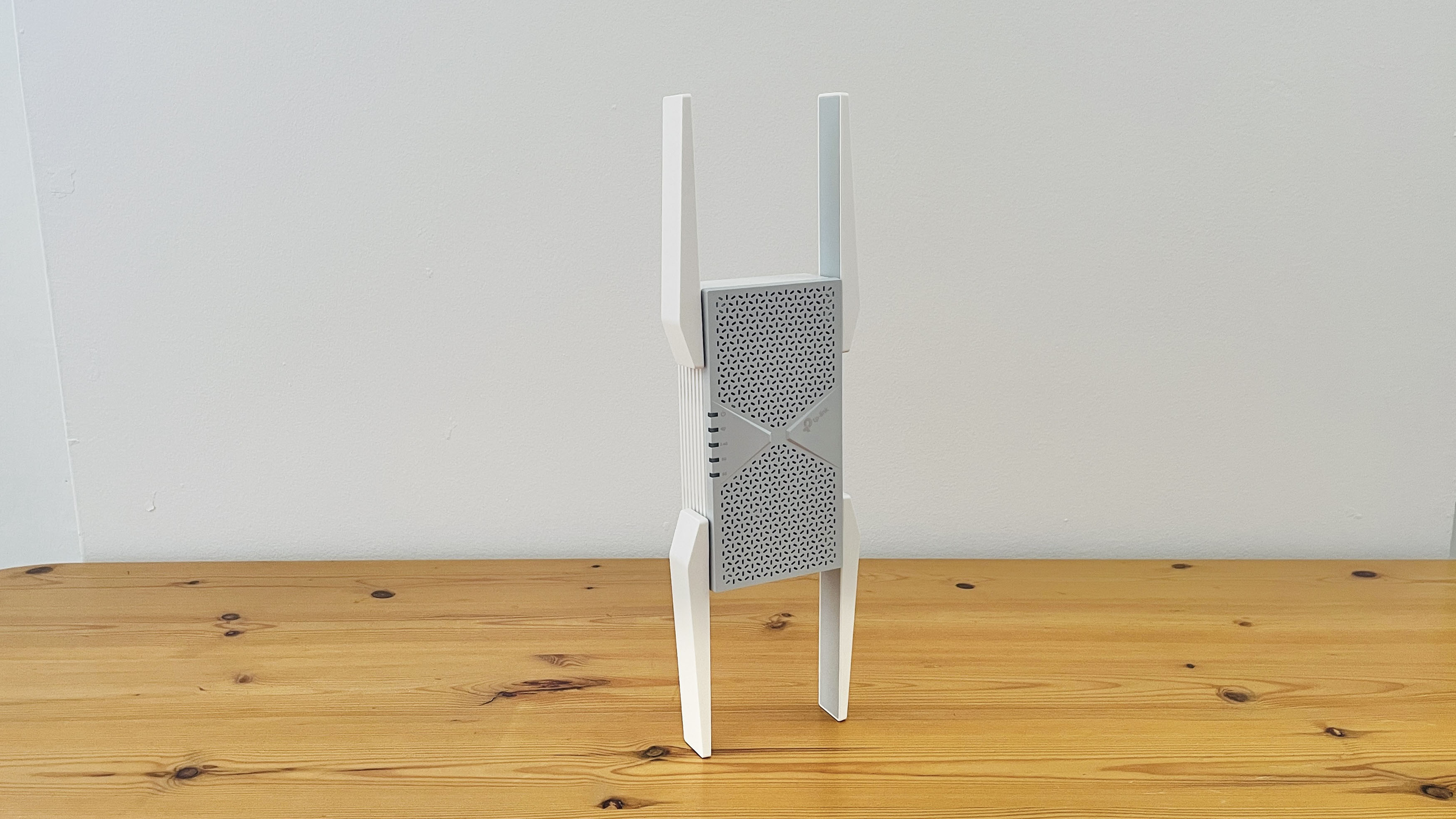 TP-Link BE10000 Wi-Fi range extender on wooden desk