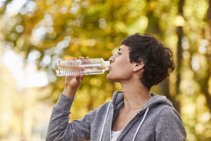 Woman drinking from water bottle, how to drink more water