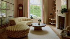neutral living room with a stone fireplace, gallery wall, a round coffee table, and a curved sofa with yellow check upholstery