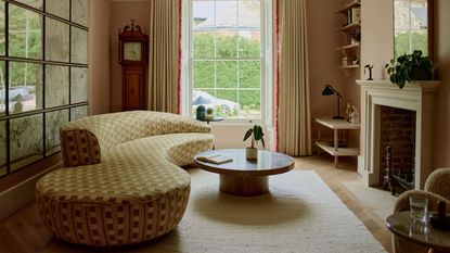 neutral living room with a stone fireplace, gallery wall, a round coffee table, and a curved sofa with yellow check upholstery