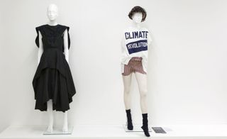 A mannequin wearing a black, layered dress beside a mannequin wearing a white t-shirt with the words "Climate Revolution"