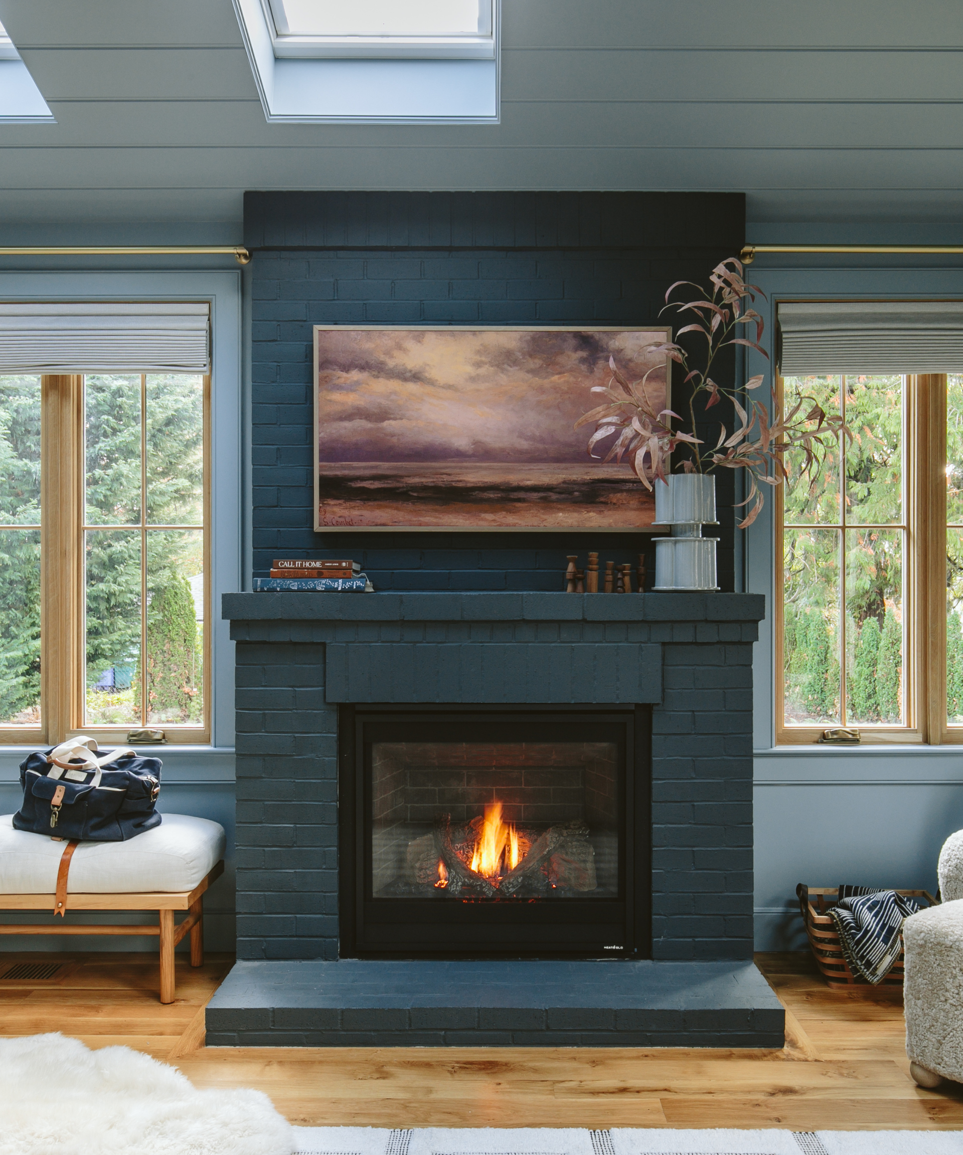 A blue fireplace with a bench on one side and windows on either side.