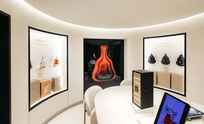 New Hennessy boutique in Harrods with a white table and chairs and Hennessy bottles displayed on the walls
