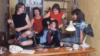 AC/DC pose behind ah office desk at their record label, 1976