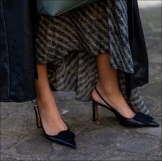 PARIS, FRANCE - JANUARY 20: Model Alizée Ekwakwe Priso wears dress, black leather coat, green bag, heels outside Loewe during the Menswear Fall/Winter 2024/2025 as part of Paris Fashion Week on January 20, 2024 in Paris, France. (Photo by Christian Vierig/Getty Images)