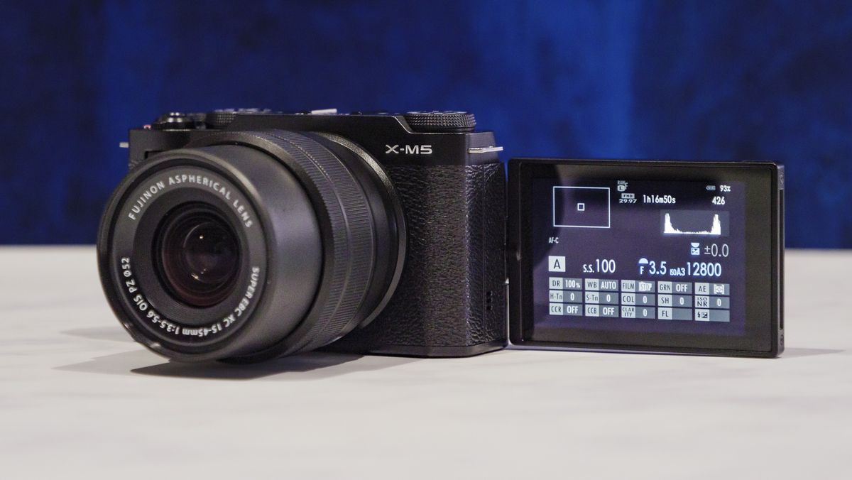 Fujifilm X-M5 camera with flip screen out, on a marble surface with rich blue background