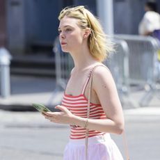 Elle Fanning wearing a red and white tank top and white skirt in NYC