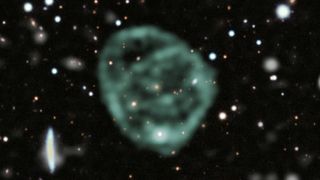 A strange blob of green circles around a galaxy in deep space