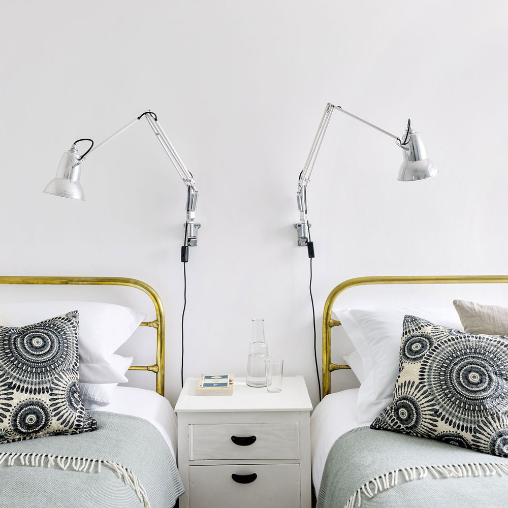 Twin bedroom with wall-mounted bedside lamps and shared side table