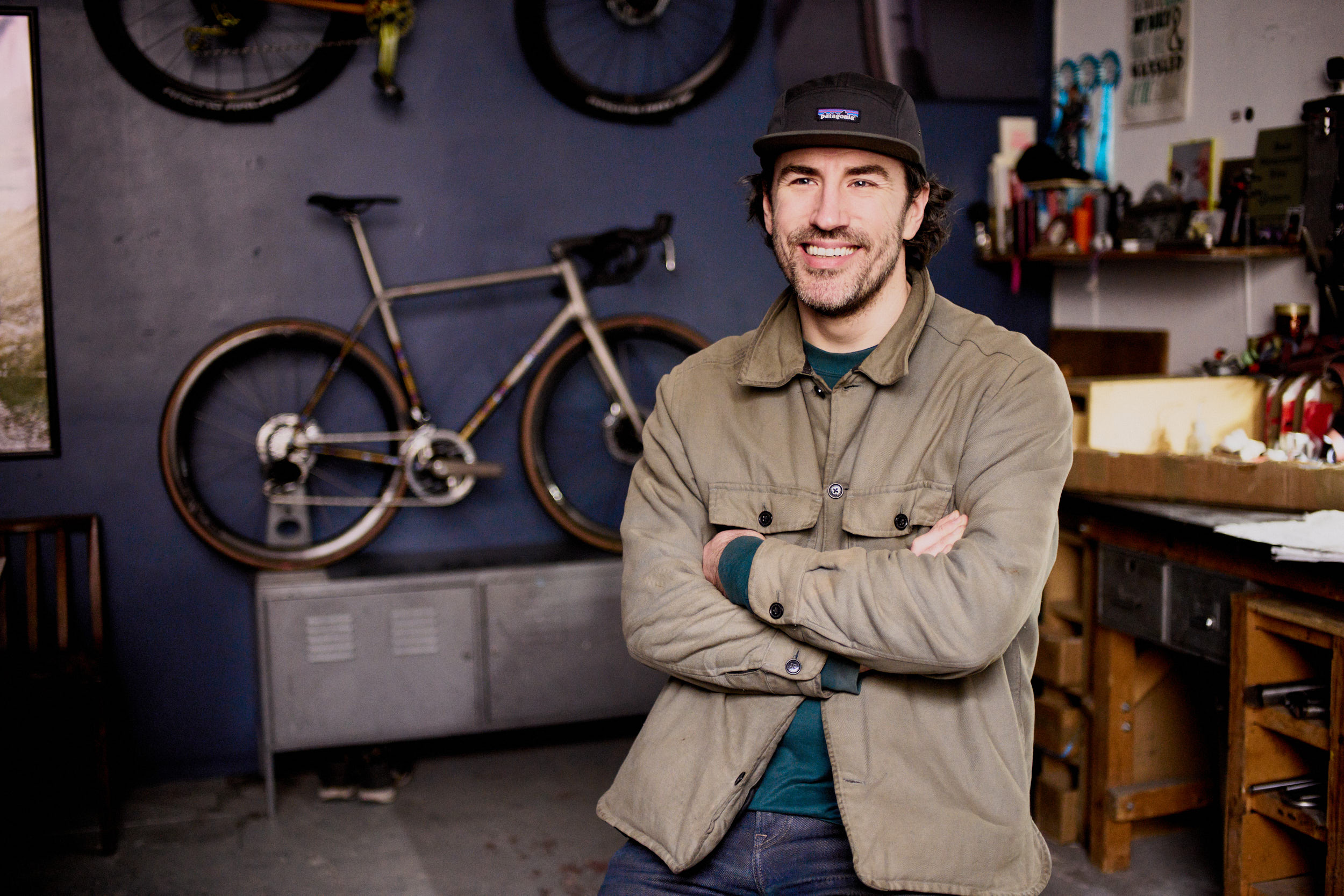 Rob Quirk, standing in his workshop in front of a bicycle mounted on the wall 