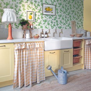 Yellow kitchen with curtain over cupboard.