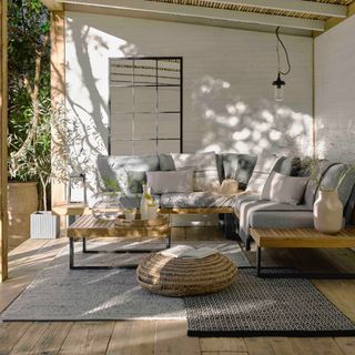 decked outdoor area undercover with L-shaped sofa, rugs, outdoor mirror, lighting, stripe cushions, coffee table