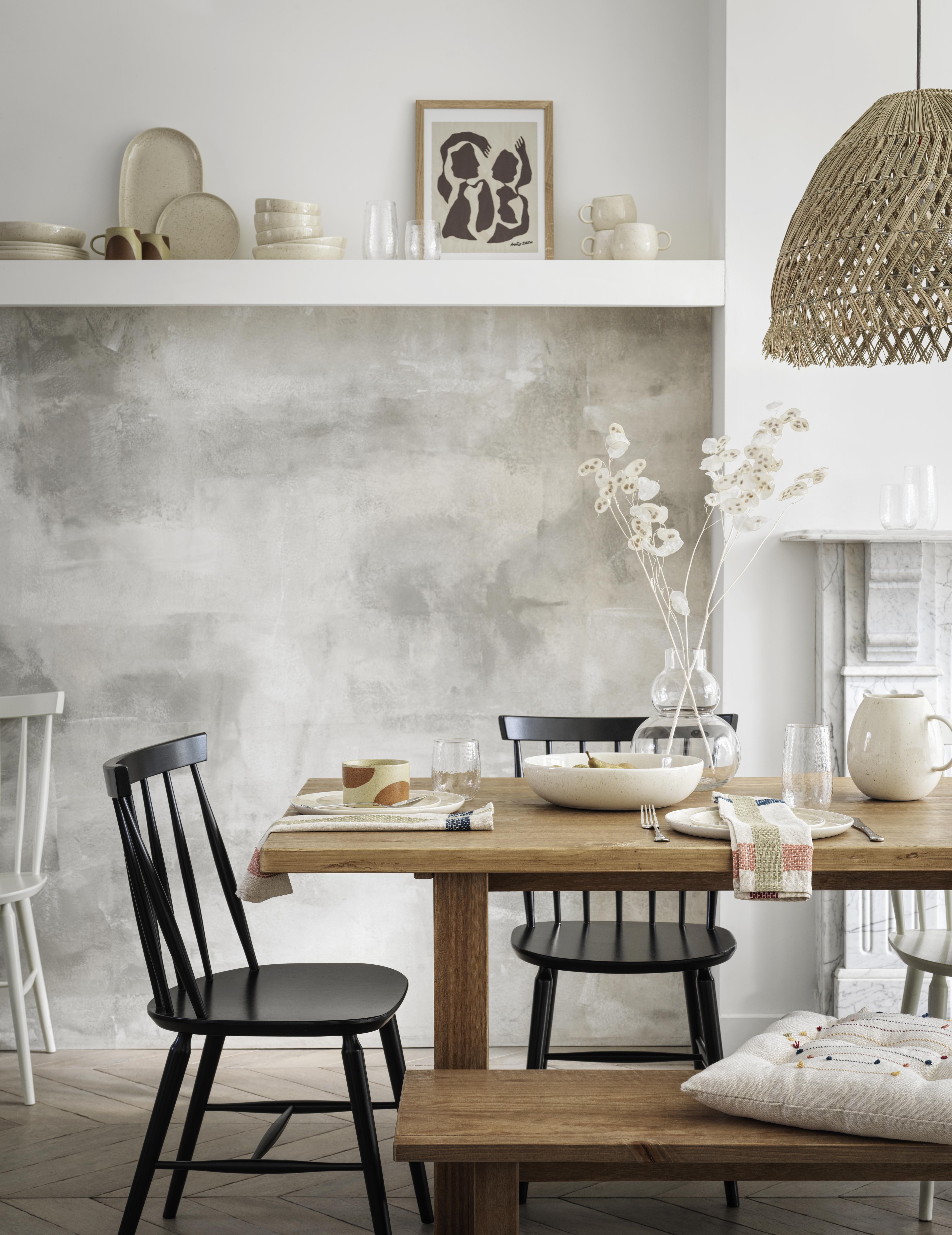 rustic dining room with paint effect wall, rattan lampshade, black chairs, ceramics on shelf