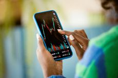 woman using smart phone at home, watching share price chart perhaps of an investment trust