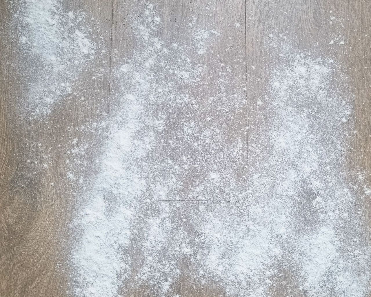 A wooden floor with flour scattered on it