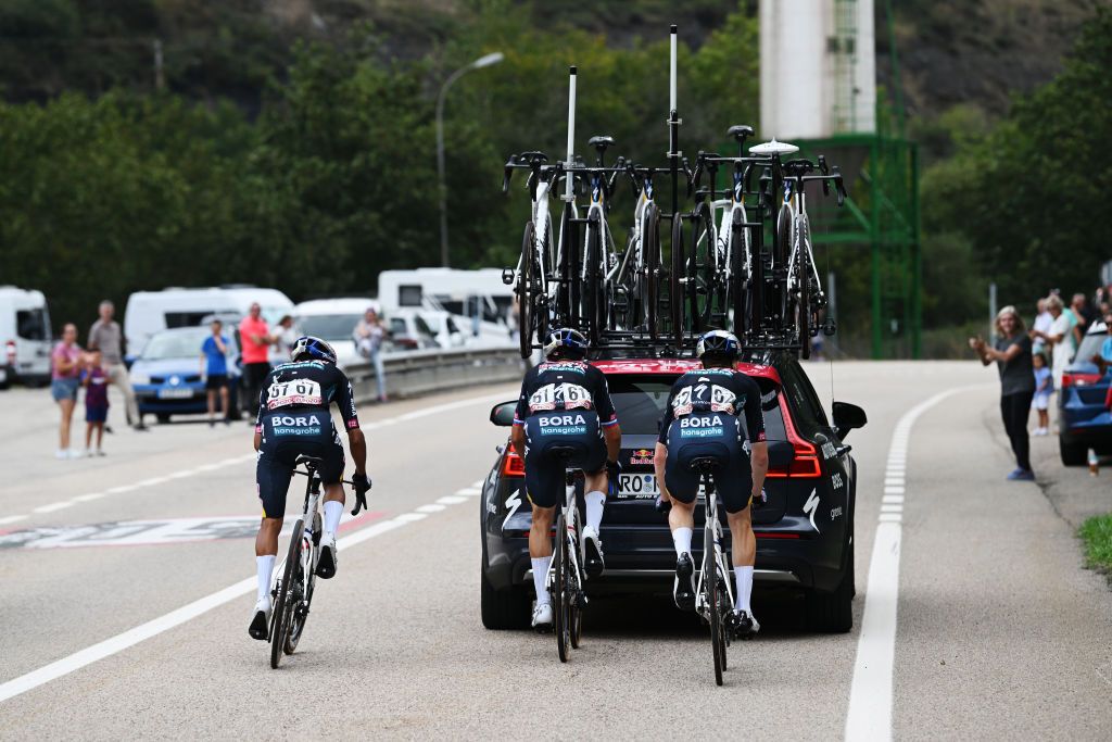 Primoz Roglic chasing back from a bike change behind the Red Bull-Bora-Hansgrohe team car on stage 15 of the Vuelta a Espana 2024