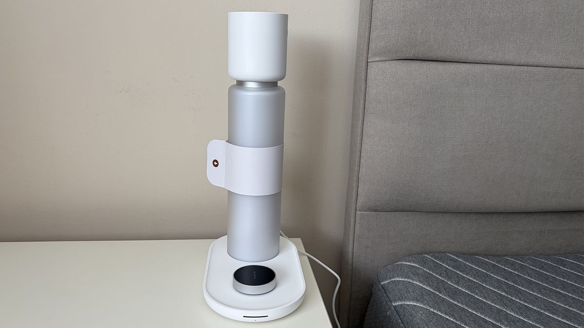 The Sleepal AI Lamp on a nightstand next to a mattress in the reviewer's bedroom, with the tag still on.