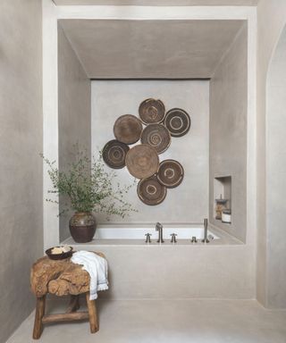 pale grey bathroom with square bath nook and woven plates on walls