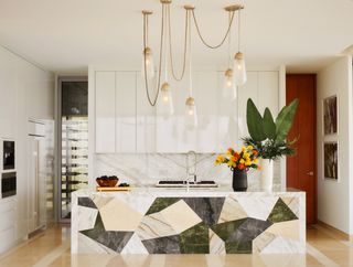 multi-colored marble island in kitchen with multiple pendant lights