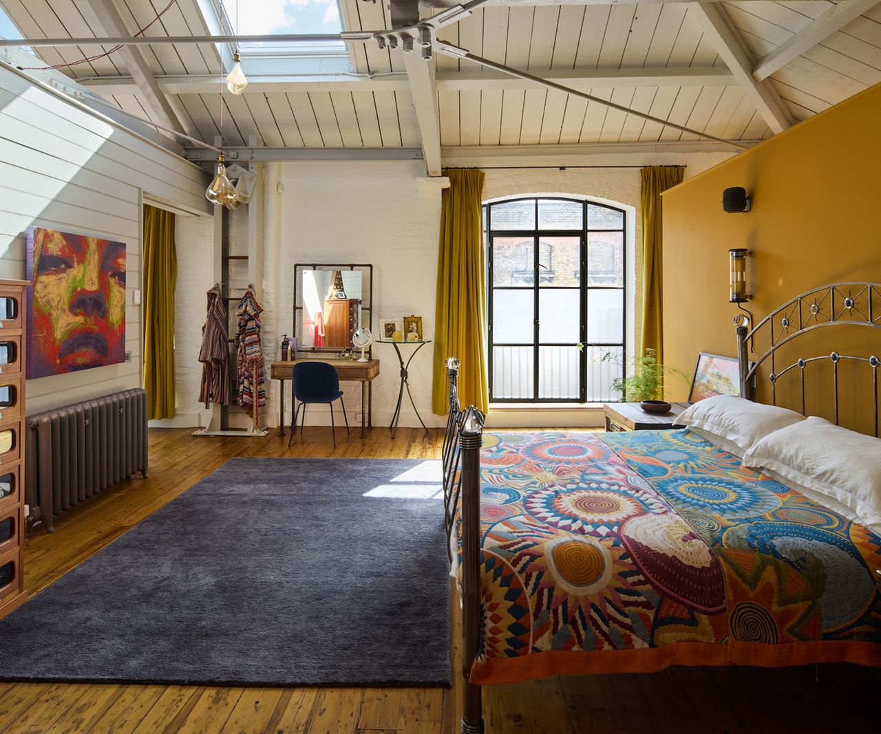 A bedroom with yellow walls and a vaulted ceiling with a rooflight