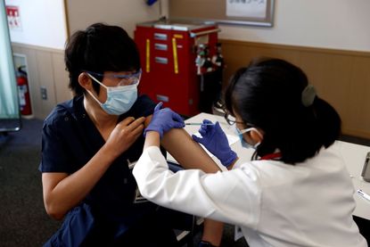 A medical worker in Tokyo receives a COVID-19 vaccine.