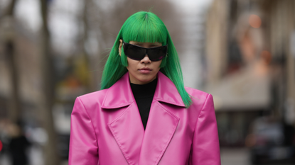 A guest wears black futurist sunglasses, a black turtleneck wool pullover, a neon pink shiny leather oversized blazer jacket, outside Palm Angels, during Paris Fashion Week - Womenswear Fall Winter 2023 2024, on March 05, 2023 in Paris, France. 