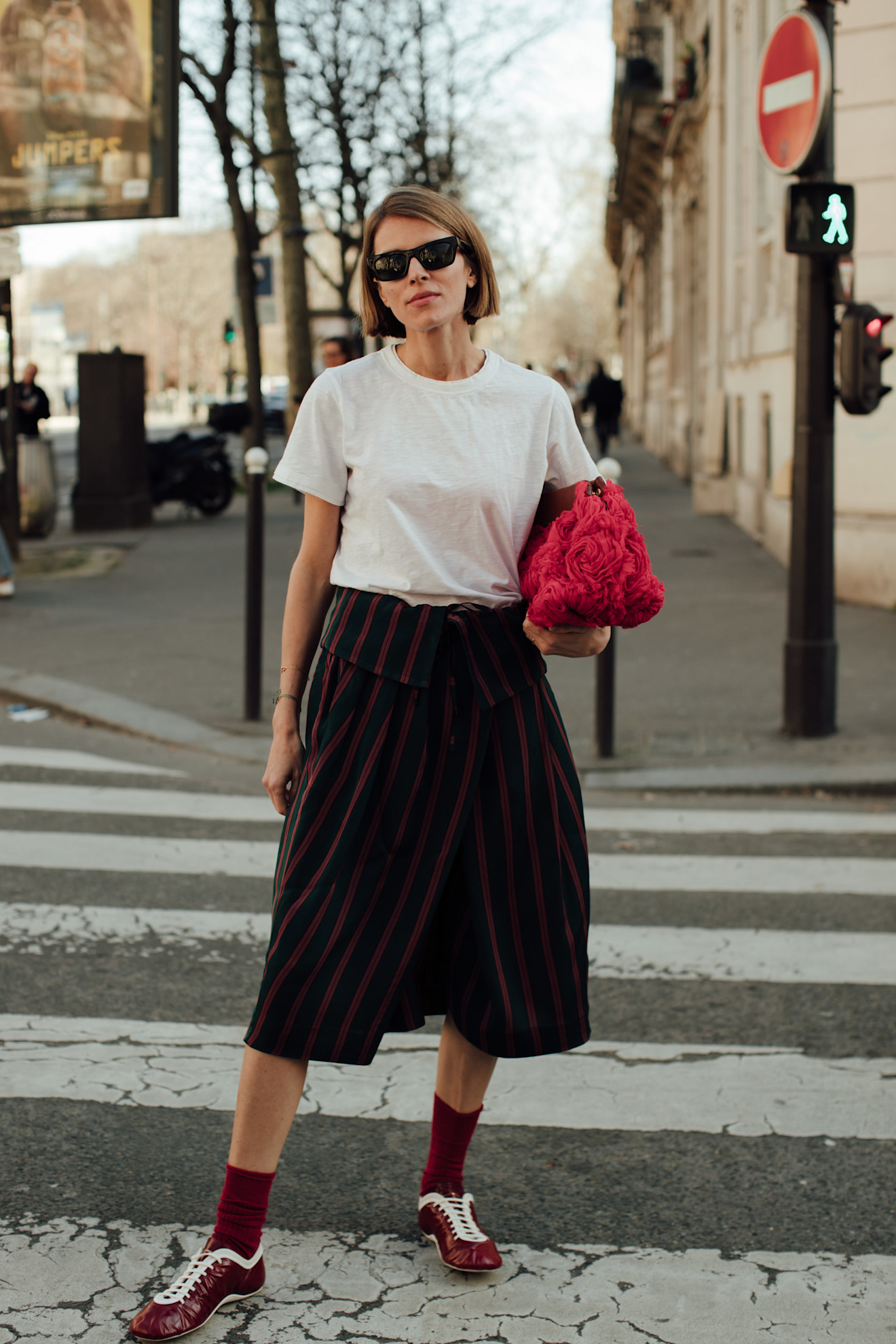 Woman wearing brown sneakers, bermuda shorts, and a white t-shirt.