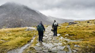 Two photographers hiking in Snowdonia, carrying camera bags