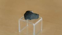 a small black rock on a clear plastic stand