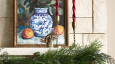 Shea McGee x Target Christmas decor styled on a mantle, including an oil painting, fluted candlesticks, and evergreen gardland