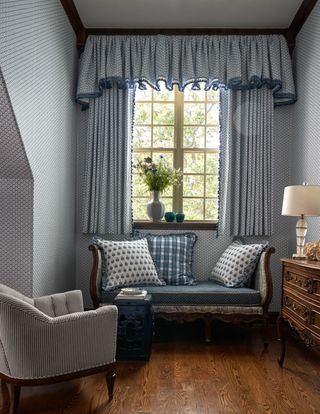 gray wallpapered bedroom with dormer window and traditional wood framed sofa and ornate curtain pelmet and upholstered armchair