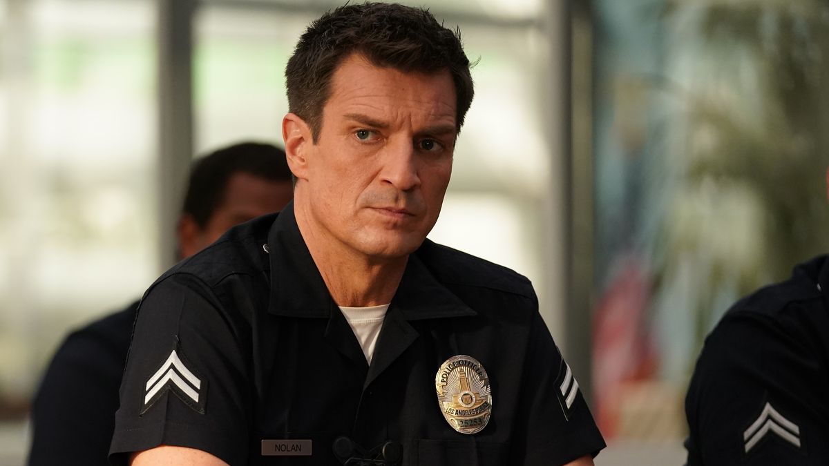 Nathan Fillion as John Nolan sitting down in a police uniform in The Rookie season 5