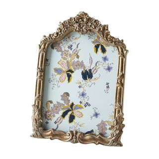 A gold ornate photo frame with a blue floral picture inside