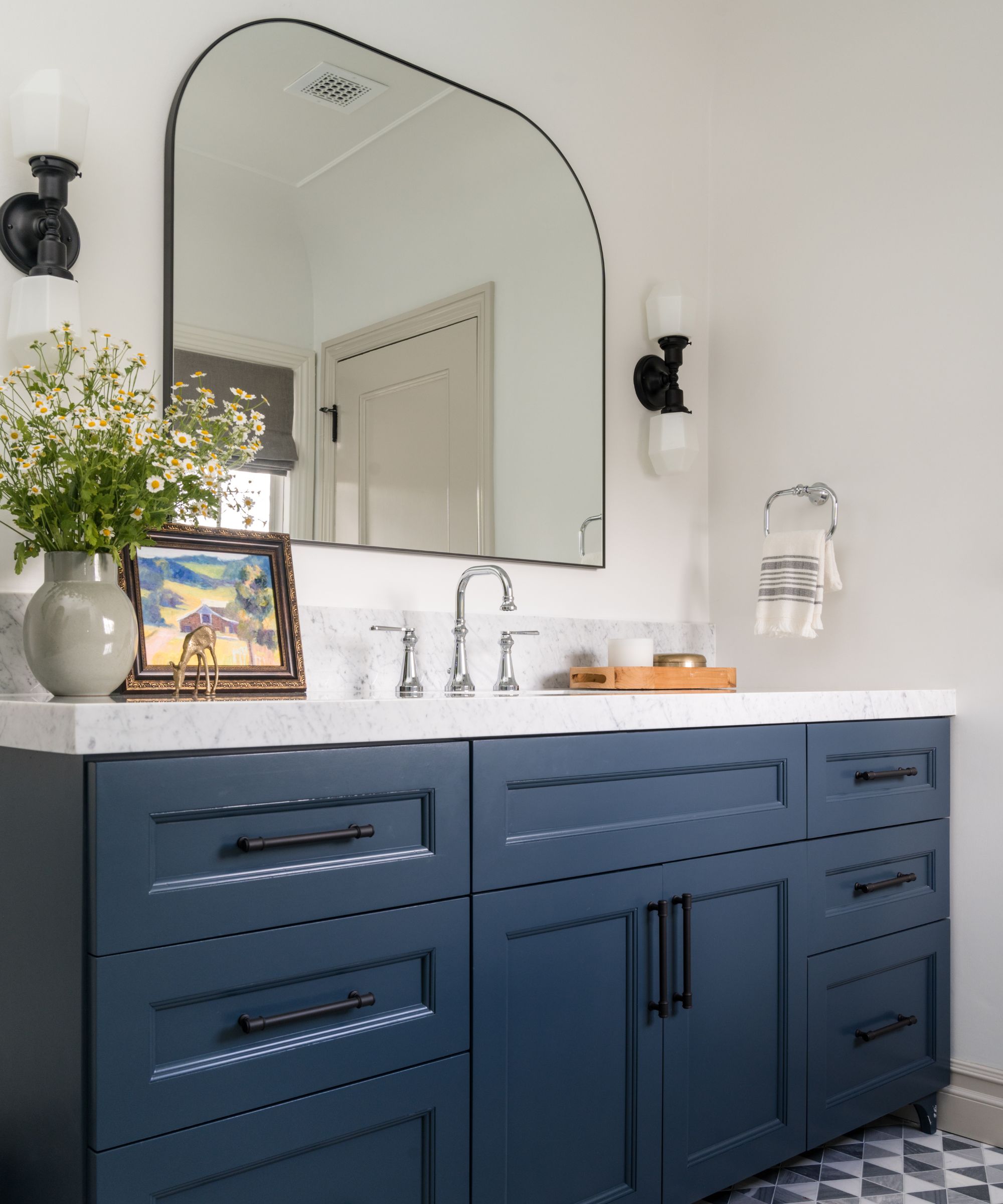 A bathroom with a large vanity mirror and dark blue cabinetry