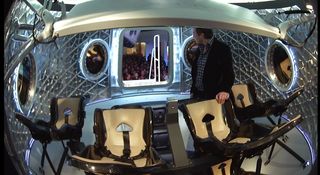 Here, Elon Musk stands in the Dragon V2 capsule, revealing its seven seats, on May 29, 2014, during a press briefing at the SpaceX headquarters in Hawthorne, California.
