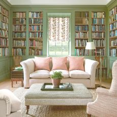 living room with green built-in bookshelves on all walls with a cream sofa