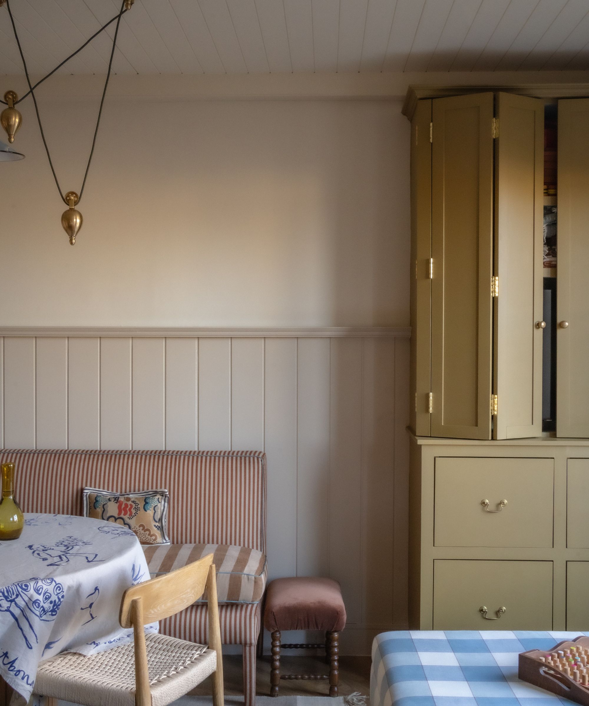 A modern rustic kitchen with an ochre dresser, taupe wall panelling and banquette seating.