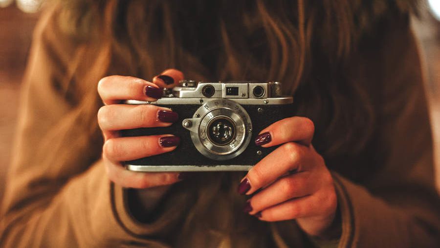 a girl holding a vintage film camera