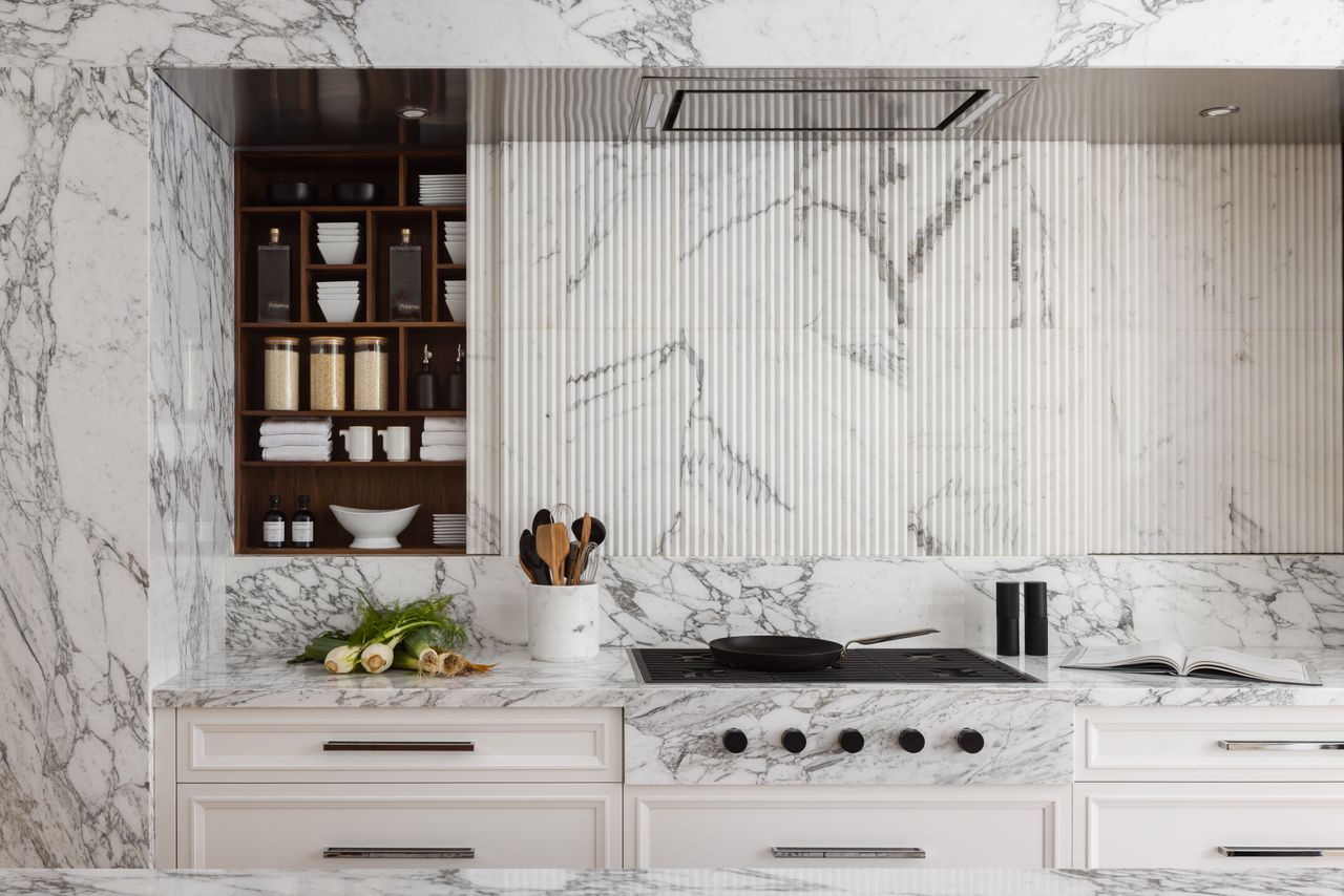 A kitchen with white marble walls, countertop and backsplash