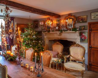 dining room in old farmhouse with gilded chairs and mirrors and stone fireplace dressed for Christmas