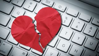 A picture of a broken heart on top of a computer keyboard
